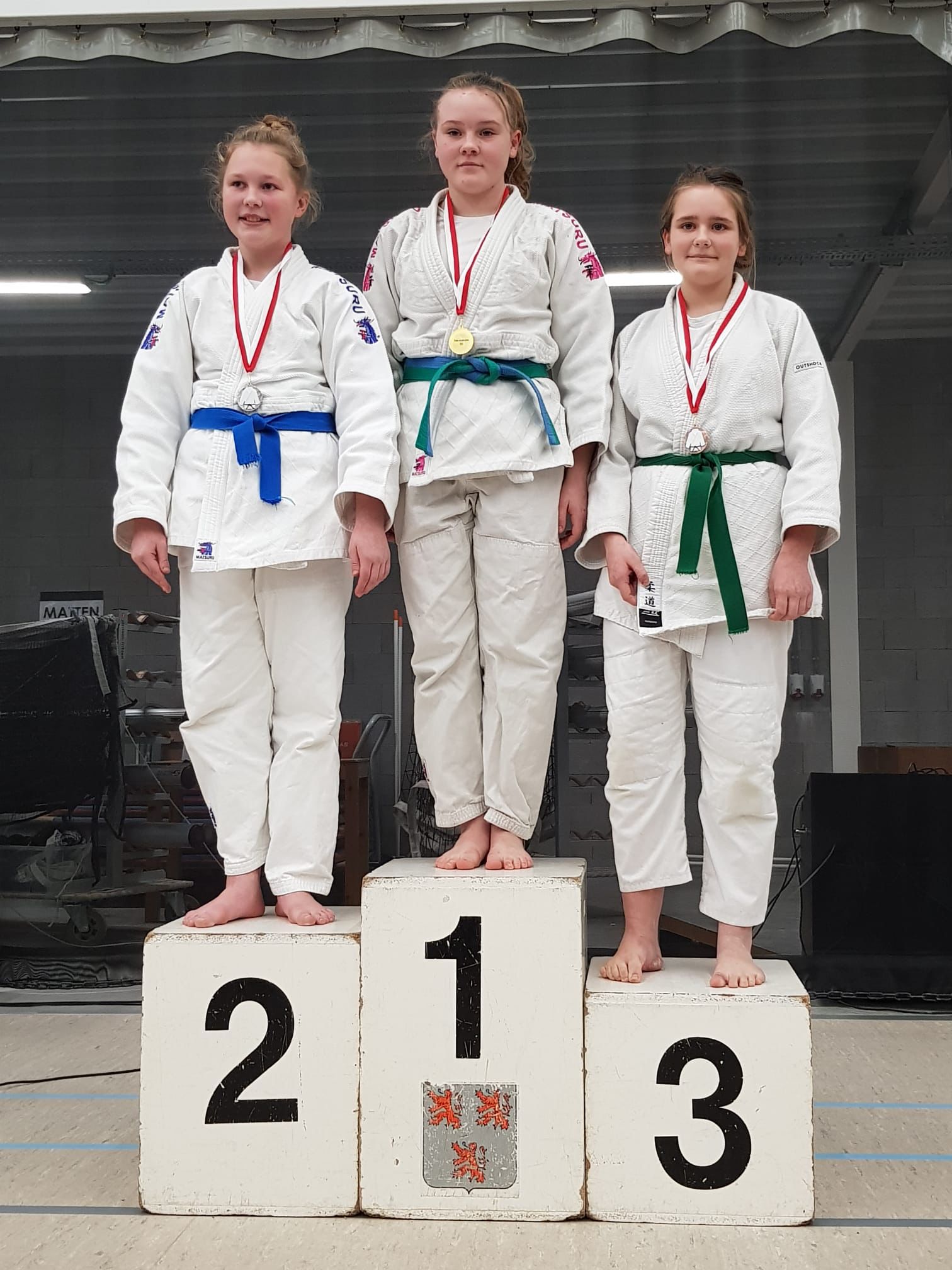 Meisjes in judogi staan op podiumplaatsen na een wedstrijd judo