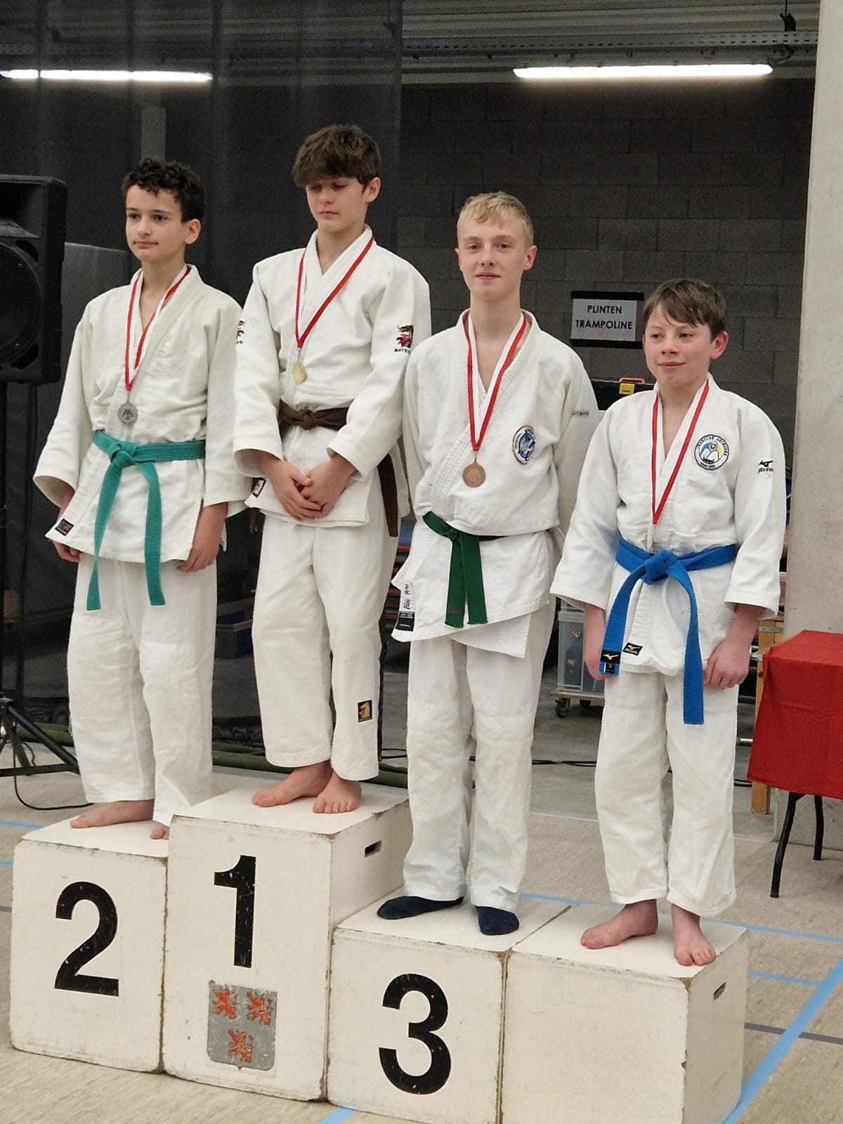 Jongens in judogi staan op podiumplaatsen na een wedstrijd judo